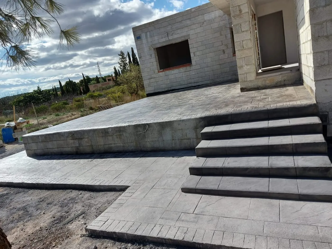 Escalera y plataforma exterior de hormigón impreso gris en una casa en obra