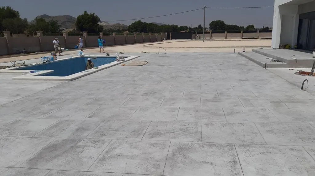 Explanada de hormigón impreso alrededor de una piscina en construcción
