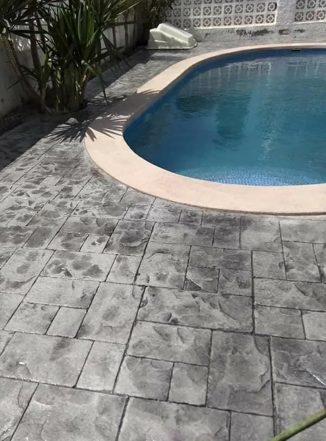 Piscina con coronación curva y pavimento de hormigón impreso gris
