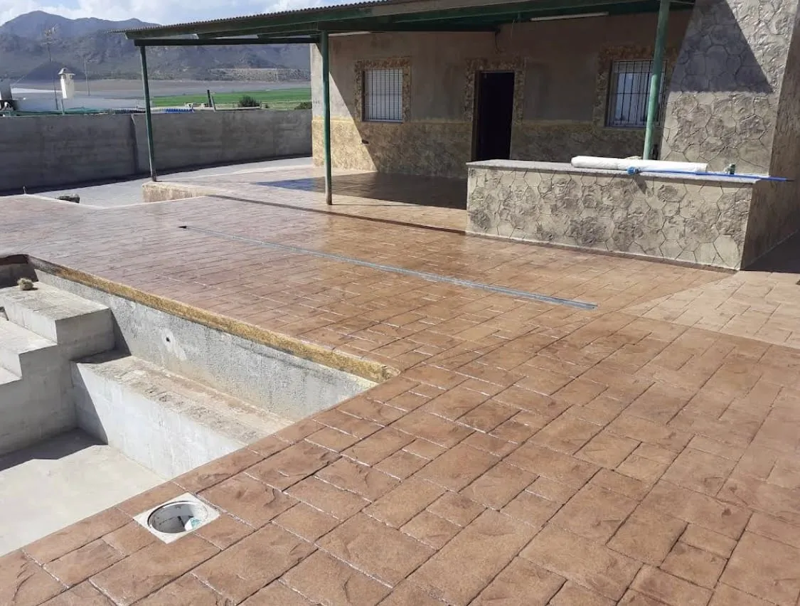 Piscina en obra con la playa de hormigón impreso terracota ya terminada
