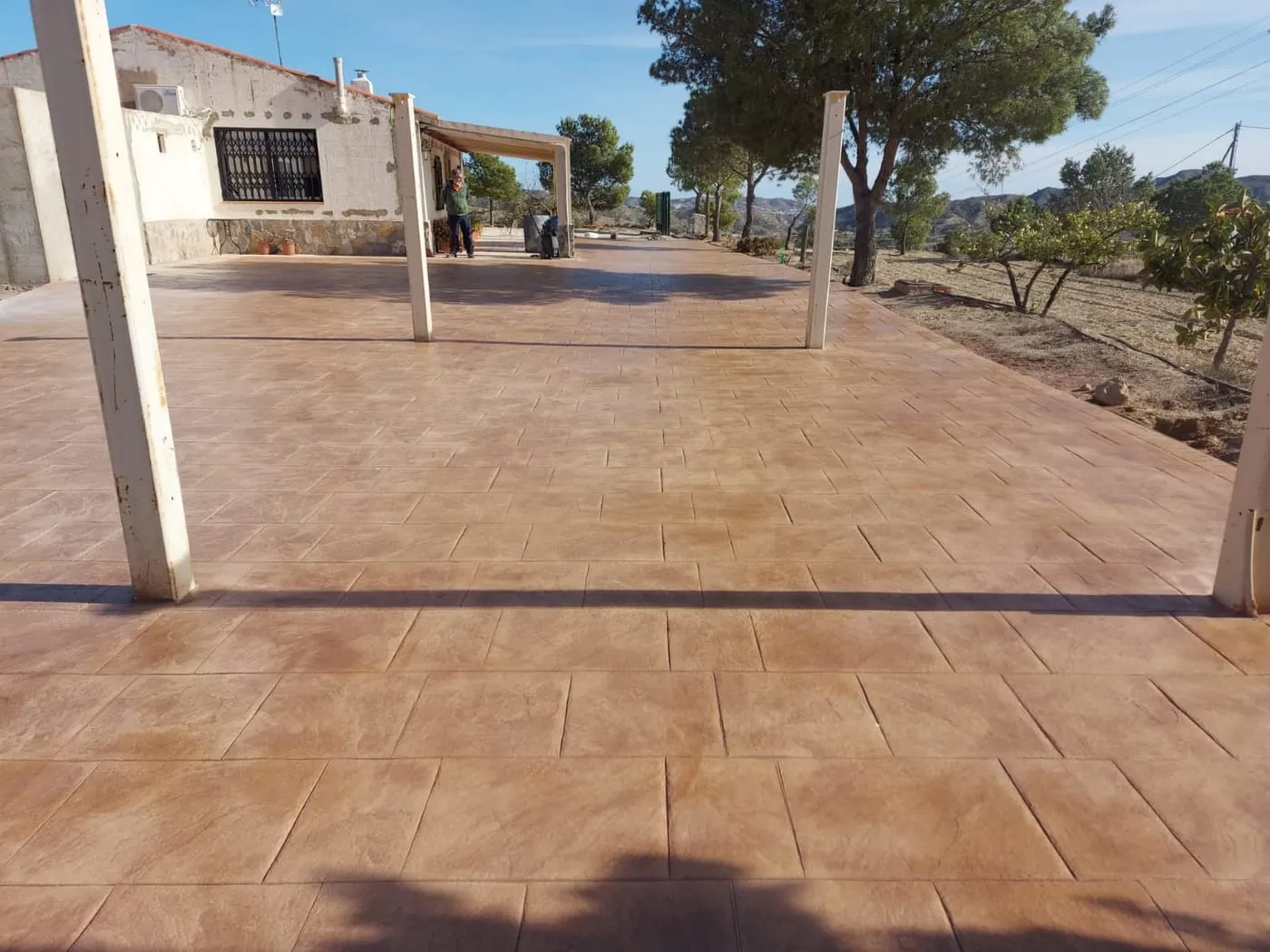 Terraza cubierta de hormigón impreso terracota delante de una vivienda